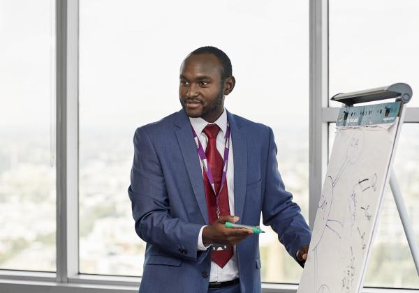 Man in a blue suit presents a mind-map to colleagues.
